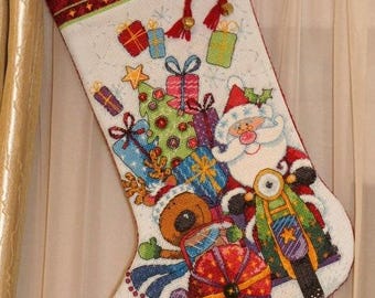 May include: Christmas stocking featuring Santa Claus on a motorcycle, surrounded by presents and a Christmas tree. The stocking is white with a red trim and the name "ALEXANDRA" at the top. Festive design.