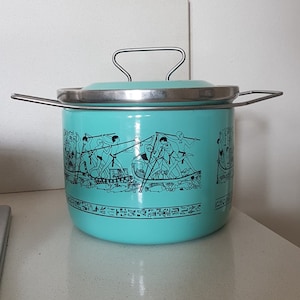 May include: A turquoise blue enamel pot with a silver lid and handle. The pot has a black and white design of Egyptian hieroglyphics and figures.