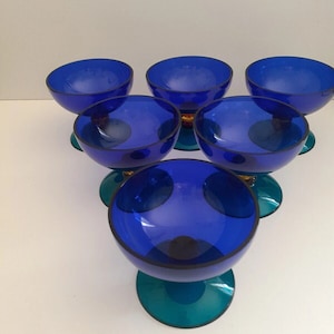 May include: Set of six blue glass dessert cups with teal green bases. The cups are clear and have a slight frosted effect.