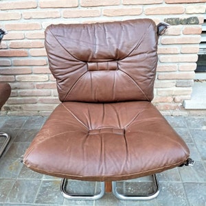 May include: A brown leather chair with a chrome frame. The chair has a tufted back and seat.