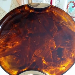 May include: A round, brown and gold tray with a marbled pattern. The tray has a gold rim and a slightly raised edge.