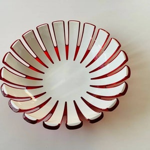 K&ouml;nnte beinhalten: Eine dekorative Schale mit einzigartigem Design. Die Schale hat ein wei&szlig;es Innen- und Au&szlig;endesign mit roten Akzenten. Der Rand weist wei&szlig;e, bl&uuml;tenblattartige Formen mit roten Details auf, die ein ansprechendes Muster bilden. Diese Schale eignet sich zum Servieren oder Dekorieren.