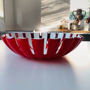 K&ouml;nnte beinhalten: Eine auff&auml;llige rot-wei&szlig; dekorative Schale mit einem einzigartigen, offenen Design. Die Schale hat abwechselnd rote und wei&szlig;e vertikale Segmente, die einen starken visuellen Kontrast erzeugen. Ideal zum Pr&auml;sentieren von Obst oder als dekoratives Herzst&uuml;ck.