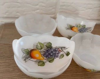Może przedstawiać: Zestaw pięciu białych ceramicznych miseczek z falistym brzegiem. Każda miseczka zdobiona jest ręcznie malowanym wzorem przedstawiającym gruszkę i winogrona na winorośli.