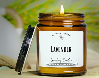 May include: A brown glass jar candle with a white label that reads "SOY WAX CANDLE", "LAVENDER", "Scentury Candles", "9 OZ | HANDMADE IN NY | NON-TOXIC". The candle is lit and the flame is visible.