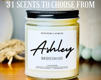 May include: A clear glass jar candle with a black lid and white label. The label says "Scentury Candles", "Ashley Bridesmaid", "Lavender", "Soy Wax Candle | Handmade in NY".