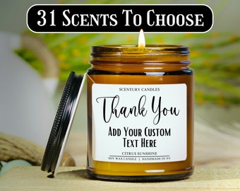 Può includere: Un barattolo di vetro marrone con una candela e un'etichetta bianca su cui è scritto "Scentury Candles Thank You Add Your Custom Text Here Citrus Sunshine Soy Wax Candle Handmade in NY". La candela è accesa e il barattolo ha un coperchio nero.