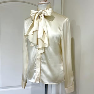 Camicetta di seta color crema, stile vintage Lavallière, con bottoni e fiocco a forma di gatto.