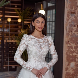 modest wedding dress, floral lace top with long sleeves, lace sleeves are puffed on the shoulders, boat neckline, corset with built-in bra and ribbon fastening on the back, a line tulle skirt is adorned with lace appliques on the top