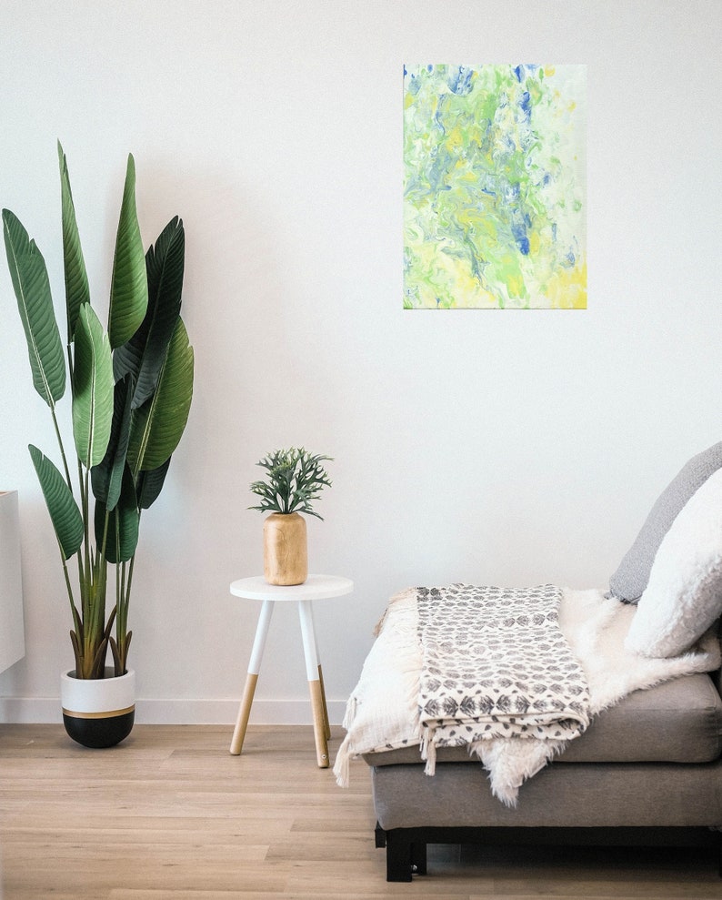 Pode incluir: Pintura abstrata com cores azuis, verdes e amarelas em espiral sobre um fundo branco. A pintura est&aacute; pendurada em uma parede branca em uma sala de estar.