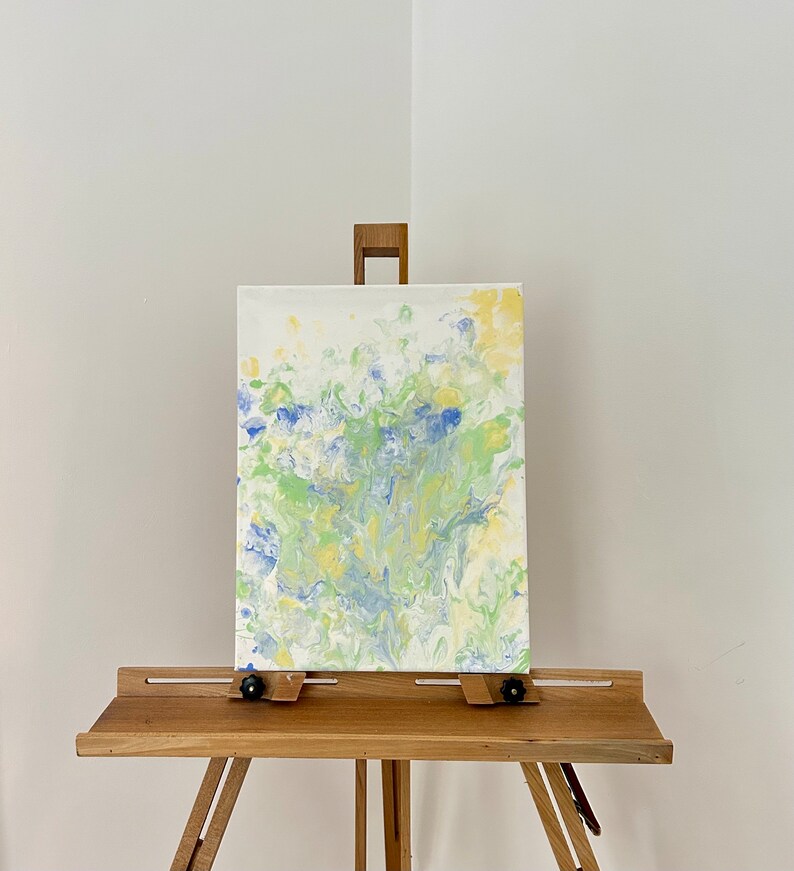 Pode incluir: Pintura abstrata em tela com um padr&atilde;o de pintura azul, verde e amarelo em espiral. A pintura &eacute; exibida em um cavalete.
