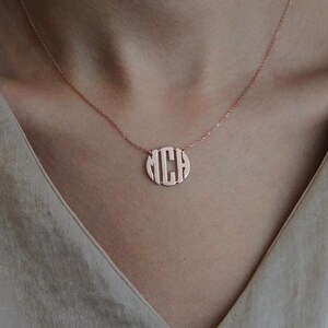 May include: A rose gold necklace with a circular pendant featuring the letters "M C H" in a monogram style.