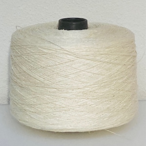 May include: A large spool of natural white yarn, wound tightly and ready for use in crafting projects.