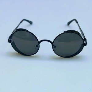 May include: Black round sunglasses with a metal frame and dark lenses.