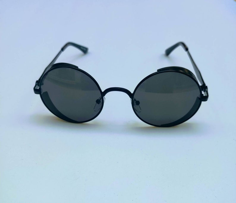 May include: Black round sunglasses with a metal frame and dark lenses.