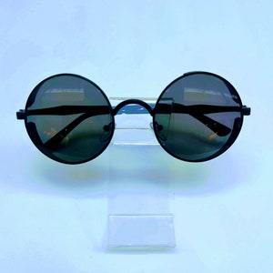 May include: Black round sunglasses with a thin metal frame. The lenses are dark and reflective.