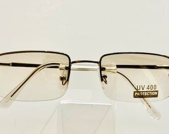 May include: A pair of rimless, rectangular-shaped sunglasses with a brown tint. The sunglasses have a metal frame and the lenses have "UV 400 PROTECTION" printed on the right lens.
