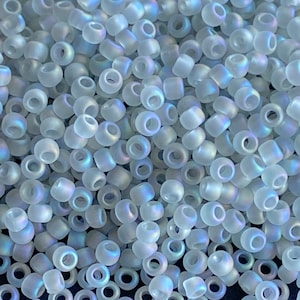 May include: A pile of small, round, iridescent white glass beads. The beads have a frosted finish and are ideal for jewellery making.