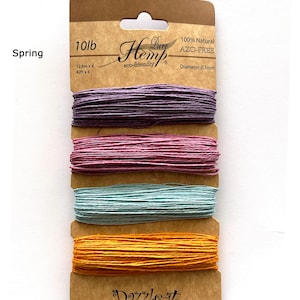 Puede incluir: Cuatro carretes de hilo de cáñamo 100% natural y libre de AZO en morado, rosa, azul claro y naranja. El hilo tiene 12,8 metros de largo y 0,5 milímetros de diámetro. Los carretes están etiquetados con "Pure Hemp eco-friendly" y "Dazzle-it".