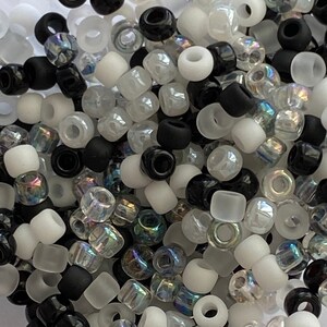 May include: A mix of black, white, and iridescent glass beads. The beads are small and round, and they are perfect for jewelry making or other craft projects.