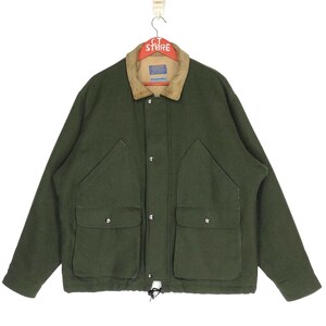 Puede incluir: Una chaqueta de lana verde oscuro con cuello de pana y múltiples bolsillos. La chaqueta tiene un cordón en la parte inferior y un cierre de botón.