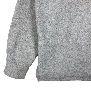 May include: A gray long-sleeved sweater with a textured knit. The sweater has a ribbed cuff and hem.