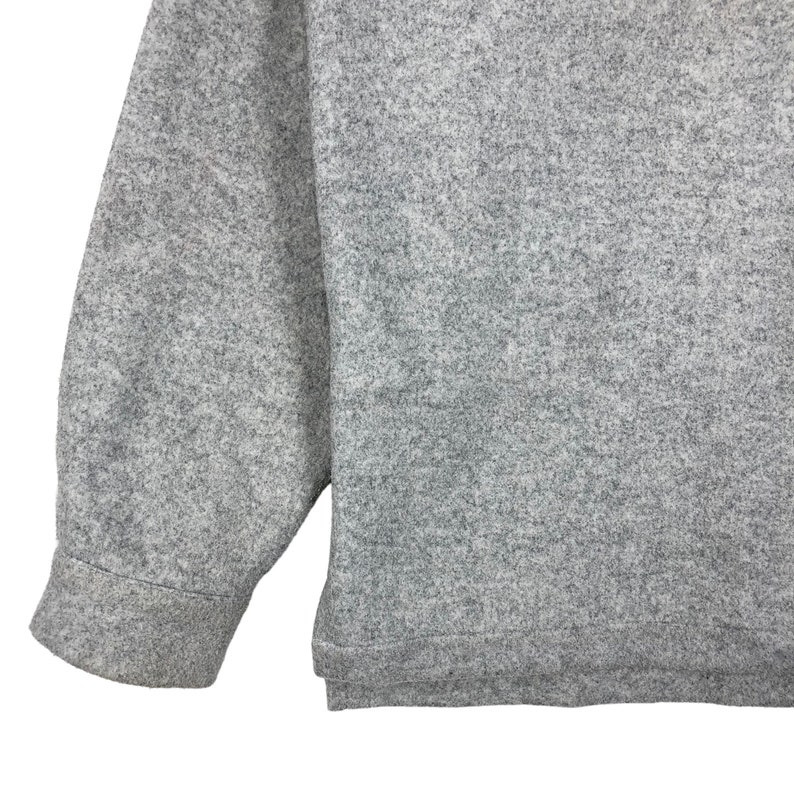 May include: A gray long-sleeved sweater with a textured knit. The sweater has a ribbed cuff and hem.