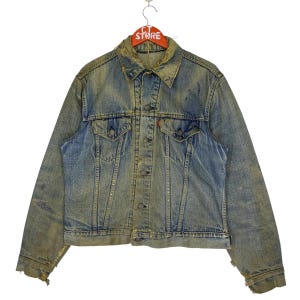May include: A vintage denim jacket with a faded blue and yellow color. The jacket has a button-up front, two chest pockets, and two front pockets. The jacket has a worn and distressed look.