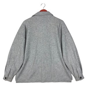 May include: A gray wool jacket with a collared neckline and long sleeves. The jacket has a button closure and two pockets.