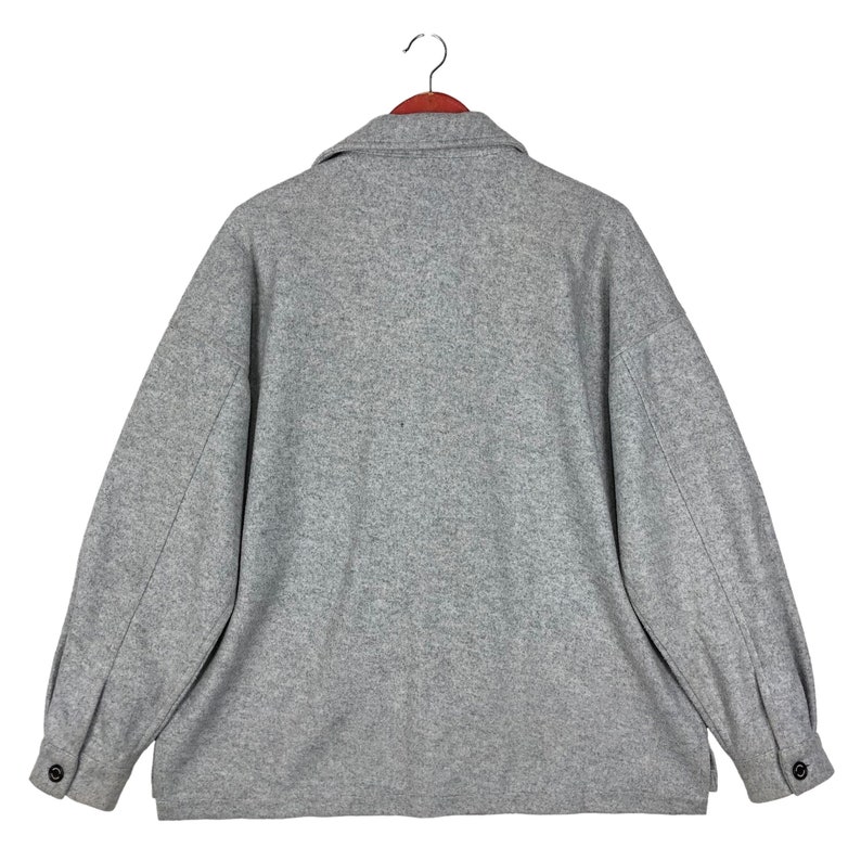 May include: A gray wool jacket with a collared neckline and long sleeves. The jacket has a button closure and two pockets.