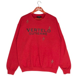 May include: Red sweatshirt with a black "VERTELO GUTIERRE" logo and small snake designs.