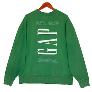 Könnte beinhalten: Grüner Crewneck-Sweatshirt mit dem Text "EST. 1969" und "GAP ORIGINAL" in Weiß.