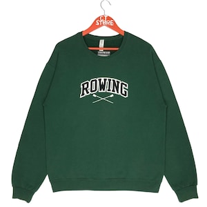Puede incluir: Una sudadera de cuello redondo verde oscuro con la palabra "ROWING" en letras blancas con contorno negro. La palabra está arqueada y tiene dos remos cruzados debajo.
