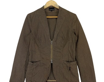 May include: A brown and tan checkered blazer with a zipper closure and two pockets. The blazer has a v-neck and a long sleeve.