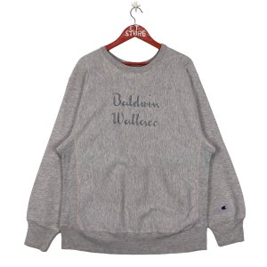 May include: A grey Champion sweatshirt with a navy blue embroidered logo on the right sleeve and the text "Baldwin Wallace" in navy blue embroidery on the front.