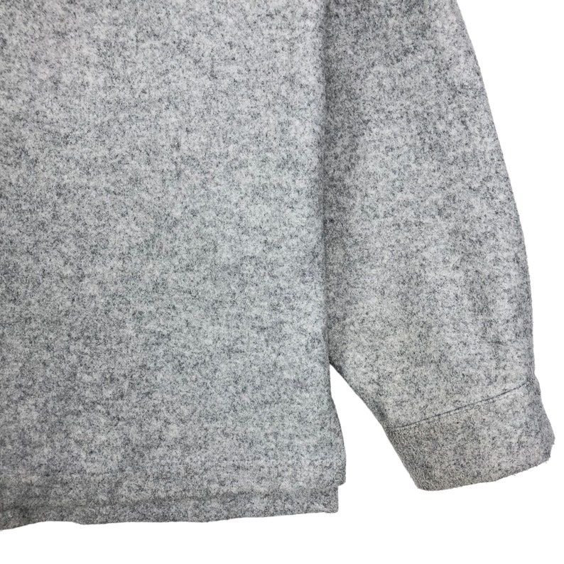 May include: A gray long-sleeved shirt made of a soft, textured fabric. The shirt has a relaxed fit and a slightly longer length.