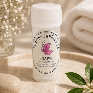 May include: A small, translucent plastic vial with a white screw-top lid. The label features a pink butterfly graphic, the text Peptide Junkies 24, SNAP-8, 1 GRAM, MANUFACTURE DATE: 11/6/25, and EXPIRATION DATE: 11/6/27 in black lettering.