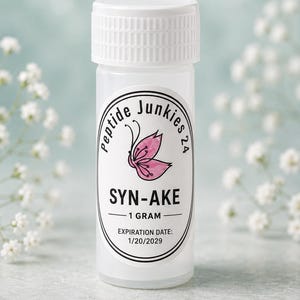 May include: A small, translucent plastic vial with a white screw-top lid. The label features a pink butterfly graphic, the text Peptide Junkies 24, SYN-AKE, 1 gram, and an expiration date of 1/20/2029 printed in black ink on a white background.