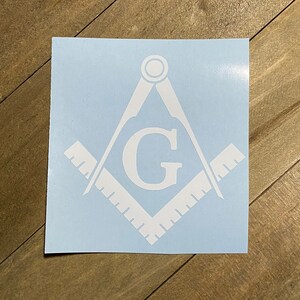May include: White vinyl decal of a Masonic compass and square with the letter "G" in the center.