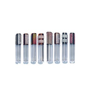May include: Eight clear lip gloss tubes with jeweled caps. The caps are decorated with rhinestones and have a rose gold finish.