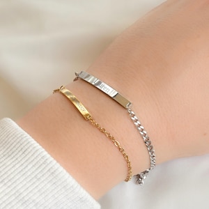 May include: Two silver bracelets with nameplates. The top bracelet has the name "Lauren" engraved on the plate. The bottom bracelet has the name "Alexandra" engraved on the plate.