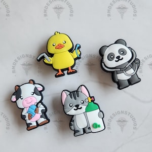 May include: Four colorful cartoon character charms, each with a different medical theme. A yellow duckling holds a stethoscope, a black and white cow holds a bottle of medicine, a gray cat holds an oxygen tank, and a black and white panda wears a stethoscope.