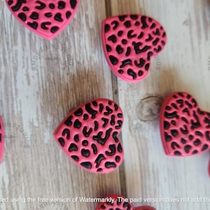 May include: Pink heart-shaped buttons with a black leopard print design.