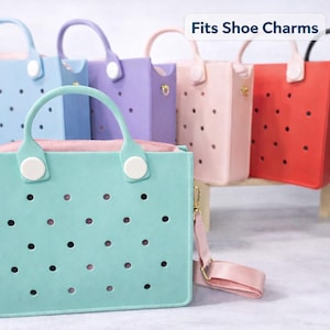 May include: A collection of colorful tote bags in various pastel shades, including mint green, lavender, and pink. Each bag features a perforated design and a top handle with a contrasting white accent. The bags have a removable shoulder strap.