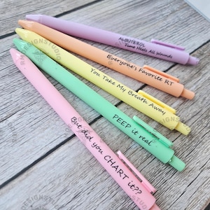 May include: A collection of five colorful pens in pastel shades of pink, green, yellow, orange, and purple. Each pen has a different phrase printed on it, including "But did you CHART it??" and "PEEP it real."