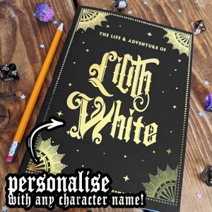 Puede incluir: Un diario negro con letras doradas que dice "The Life & Adventure of Lilth White". El diario tiene un borde decorativo y detalles de estrellas. Un lápiz y dados están al lado del diario. El texto "personalise with any character name!" también es visible.