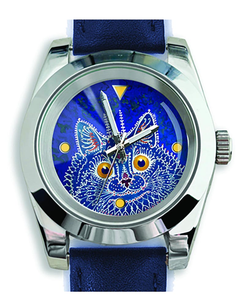 May include: A silver-toned wristwatch with a blue face featuring a detailed cat design. The cat has yellow eyes and a white and blue pattern. The watch has a blue leather band.