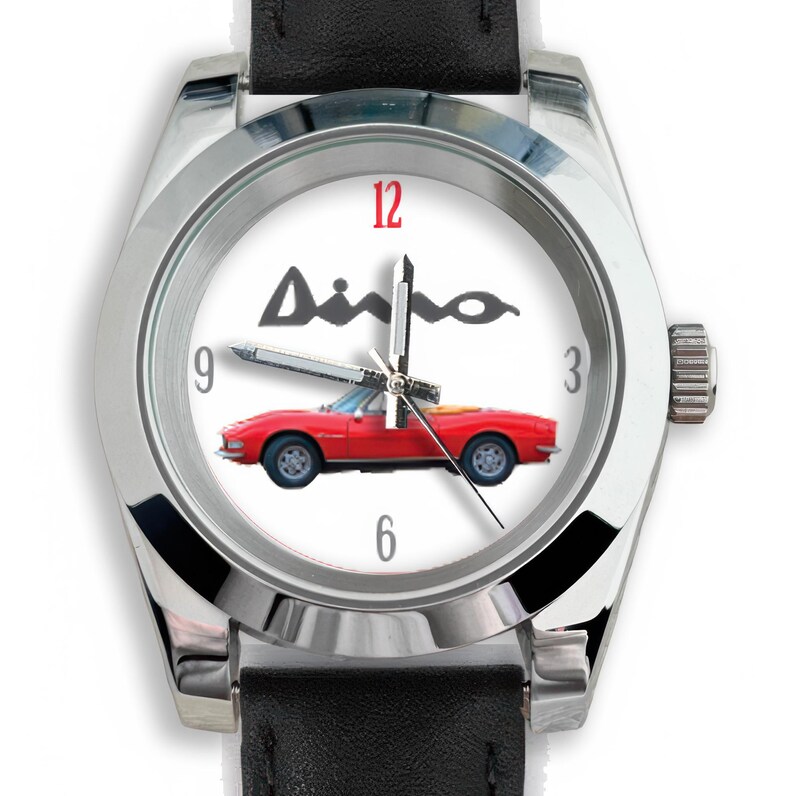 May include: A wristwatch with a white face featuring a red convertible car and the word "Ainho" in black. The watch has a silver-colored bezel, black leather band, and displays the numbers 3, 6, 9, and 12.