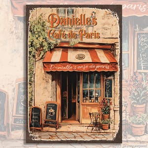 Puede incluir: Una ilustraci&oacute;n de estilo vintage de una cafeter&iacute;a parisina llamada "Danielle's Cafe de Paris". La cafeter&iacute;a tiene un toldo a rayas rojas y blancas, una gran ventana y una puerta. Hay dos pizarrones negros con men&uacute;s en la acera frente a la cafeter&iacute;a.