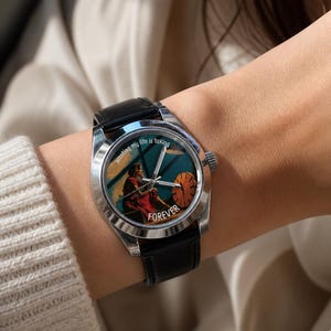 May include: A wristwatch with a black leather strap and a silver case. The watch face displays an illustration of a person in a red dress and the word "FOREVER". The text "Wasting my life is taking" is printed on the watch face.